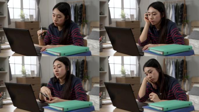 无聊的亚洲女学生在家学习正在玩笔和支撑脸，同时在计算机上观看无聊的在线视频讲座