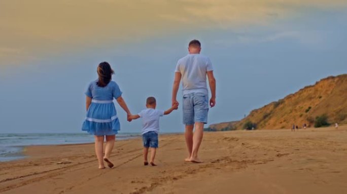 一家人带着一个小孩在海边散步，在海边散步。爸爸妈妈牵着宝宝的手，一道美丽的风景线，家庭价值连城。从后