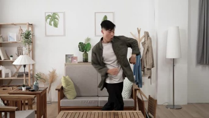 前视图，慢动作活跃的亚洲男性年轻成年人在白天在他的现代公寓里跳舞时，在原地打转。