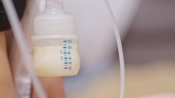 母亲为婴儿使用母乳泵。将吸奶器中的牛奶放入婴儿新生儿的奶瓶中。