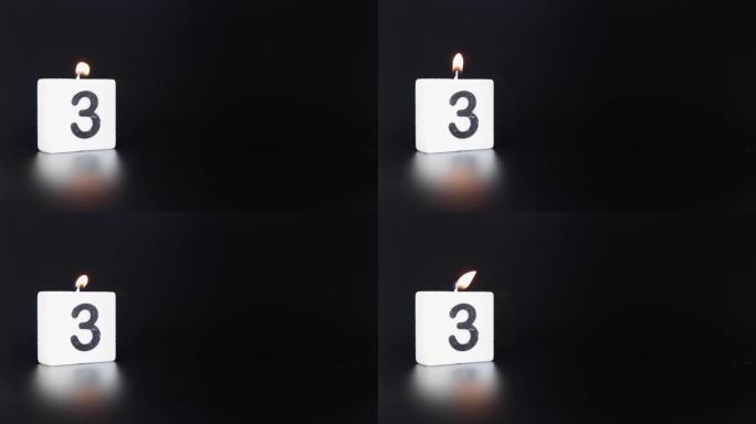 一根方形蜡烛，上面写着数字3被点燃并吹出，庆祝生日或周年纪念日。