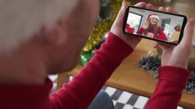 戴着圣诞老人帽子的白人男子使用智能手机进行圣诞节视频通话，屏幕上有微笑的女人