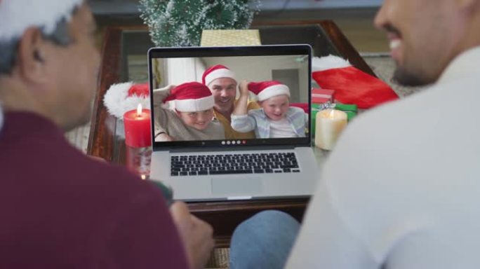 微笑的混血儿父子使用笔记本电脑与家人在屏幕上进行圣诞节视频通话