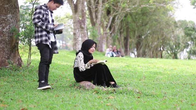 年轻夫妇坐在公园看书