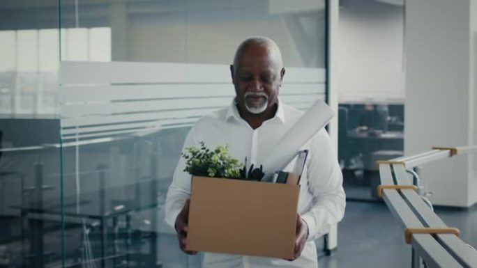 退休概念。微笑的黑人成熟员工带着财物离开办公室