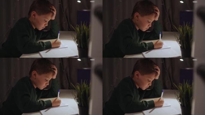 灯下男孩在家做作业的特写镜头