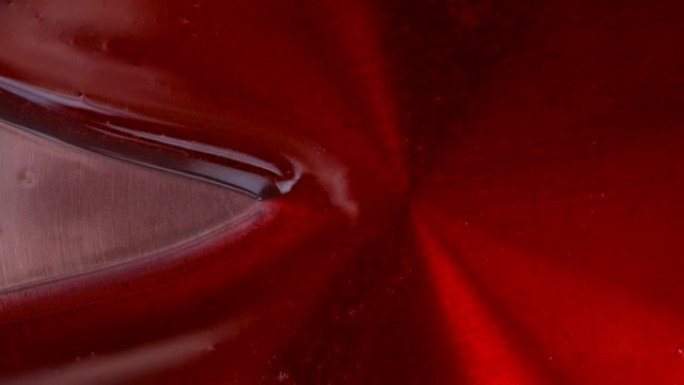 在钢锅上拍摄红色釉料的特写镜头。用白色硅胶刮刀分割焦糖釉