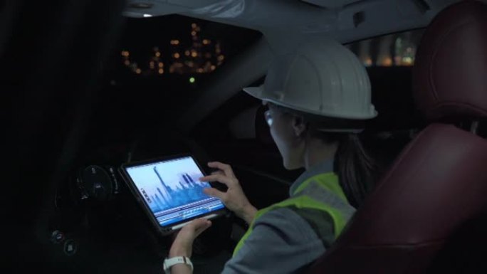 穿着制服的女主管在能源行业工作，晚上用汽车检查石化厂。