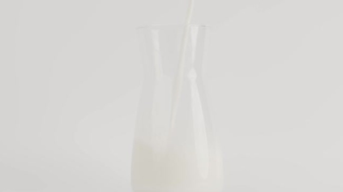 将牛奶倒入白色背景的水罐中，食物概念。