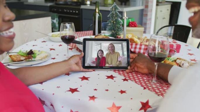 微笑的非洲裔美国夫妇使用平板电脑与屏幕上的幸福家庭进行圣诞节视频通话