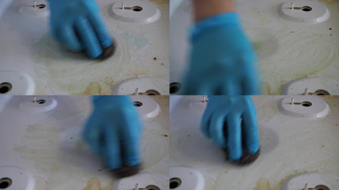 肮脏的白色煤气炉。戴手套的手擦去污垢。家庭作业。特写