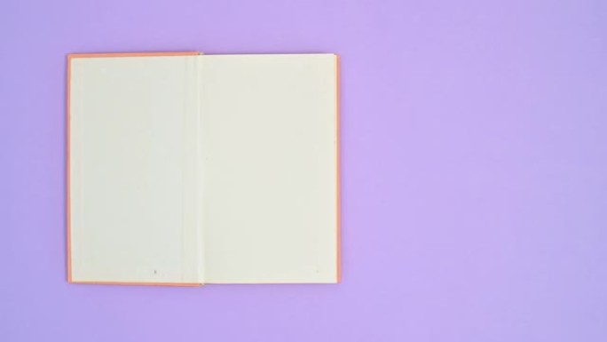 橙色精装复古书籍以紫色主题出现并打开。停止运动平铺