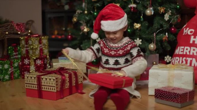 年轻女孩在家里的圣诞树旁边打开圣诞礼品盒