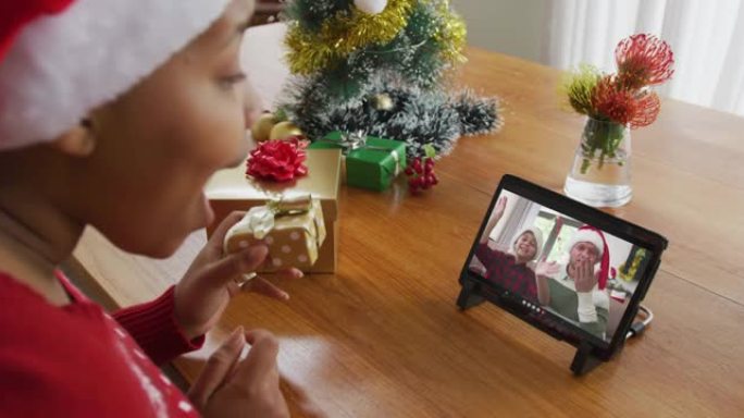 戴着圣诞老人帽子的非洲裔美国妇女使用平板电脑与家人在屏幕上进行圣诞节视频通话