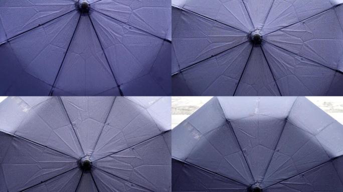雨天用水滴收上雨伞。从下到上倾斜镜头。重点放在伞布上。