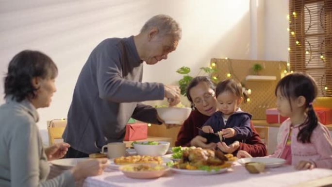 祖父母和孙子一起吃饭或吃饭，坐在一张可爱的桌子旁，参加假日聚会，互相提供食物