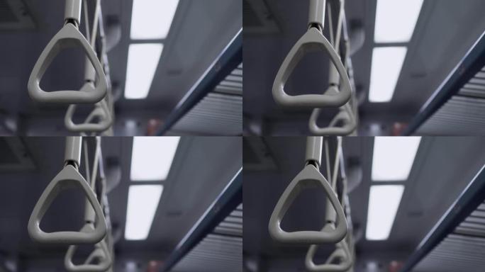 火车车厢里的手环。火车在行驶，相机轻微晃动。主题在左边。背景中有灯光。