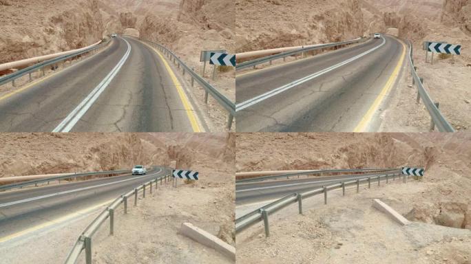 在沙漠山脉之间的道路上行驶的汽车在后视图中滑动