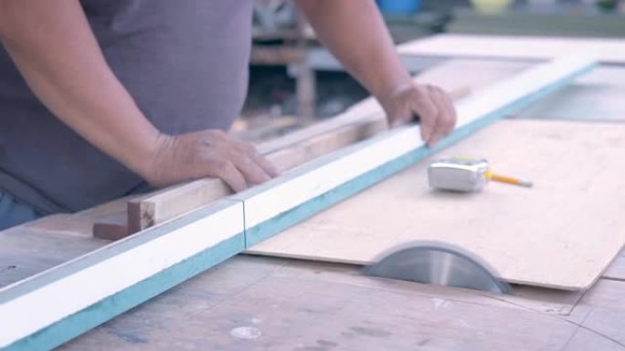 木匠使用电锯徒手切割木材以制造具有专业知识但不佩戴安全设备的内置橱柜可能会造成伤害