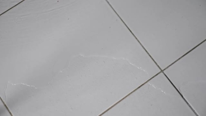 洪水流过浴室的白色瓷砖地板