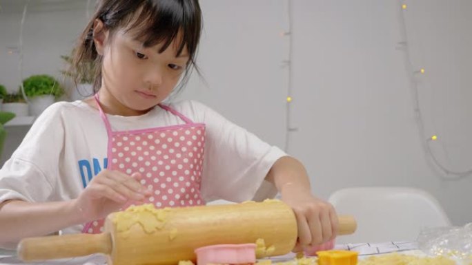 亚洲女孩在成型饼干前滚动面团，庆祝圣诞节，生活方式理念。