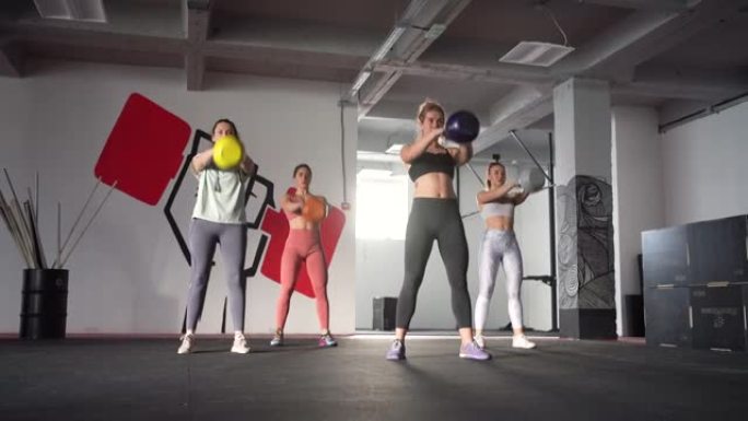 一群坚强敬业的女运动员，在健身房用哑铃锻炼