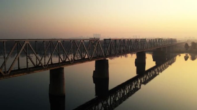 乌克兰第聂伯河上的一座铁路桥的4k视频，基辅市。无人机上的视频。沿着桥飞行。黎明。空荡荡的道路。秋天