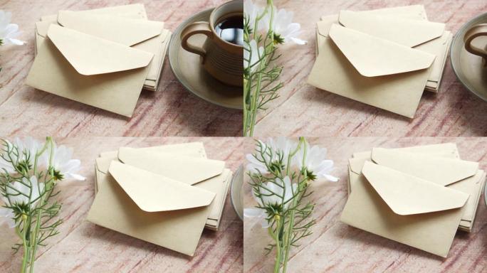 桌子上放着一堆信封，一朵花和一杯茶