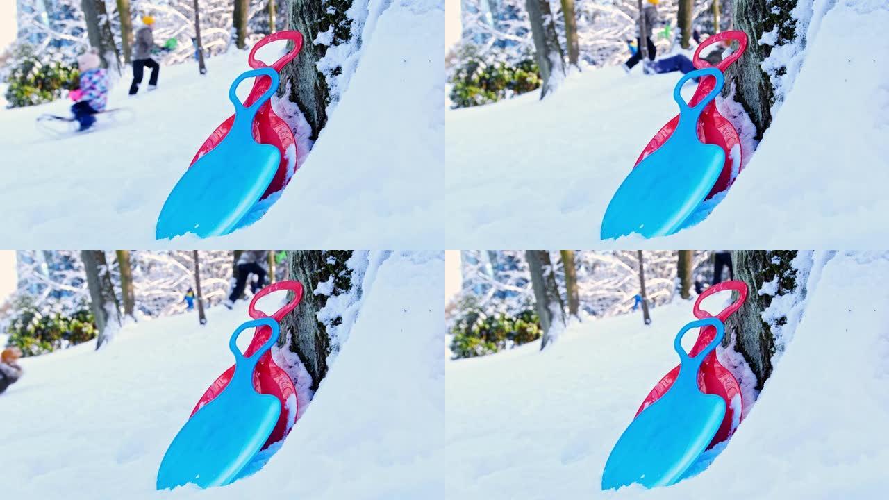 在美丽的冬日，公园树留下的滑雪机和孩子们的雪橇骑在白雪覆盖的山上
