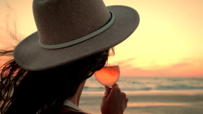 举行葡萄酒课的女人看着海洋上的日落，欣赏着令人惊叹的景色