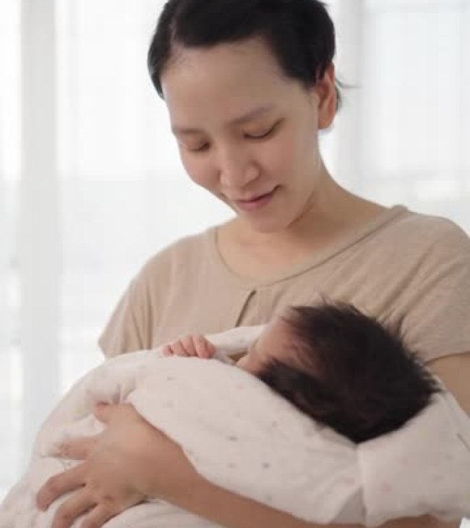 母亲为抱着摇篮曲的孩子包裹了一条毯子睡觉