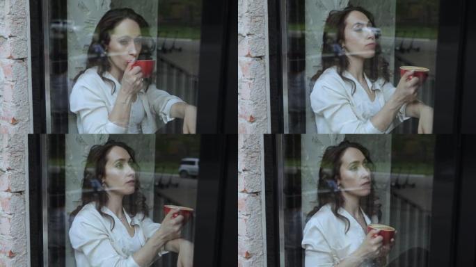 一个女人坐在窗边喝咖啡