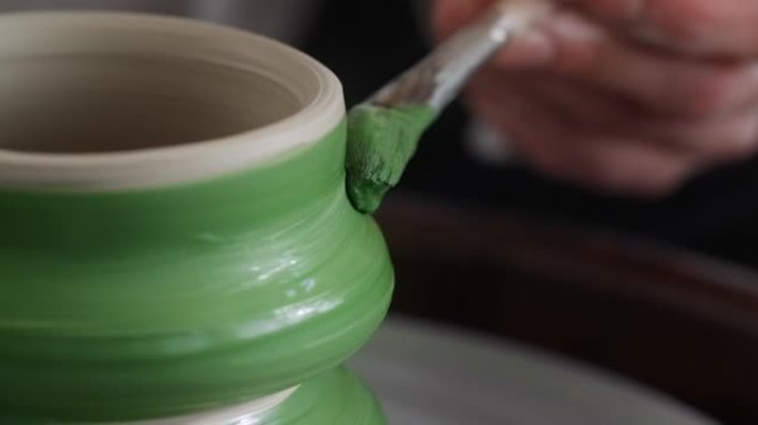 特写镜头: 波特用大刷子在波特的轮子上画一个水罐，来自陶器车间的视频，陶艺家以慢动作制作陶瓷，4k 