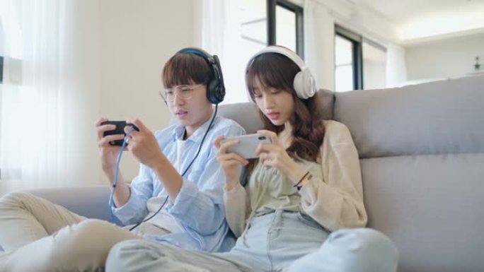 亚洲情侣情侣在假期享受和玩游戏机游戏，让更多美好的时光在家里一起快乐
