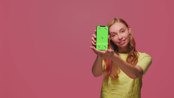 漂亮的年轻女孩展示绿屏色度键模板的手机推荐应用。广告的复制空间
