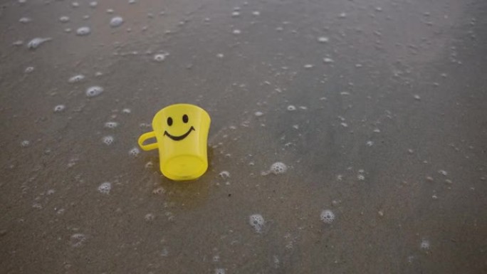 海滩沙滩上的特写黄色塑料杯。