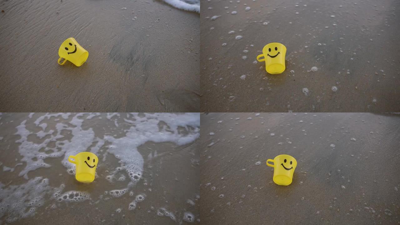 海滩沙滩上的特写黄色塑料杯。