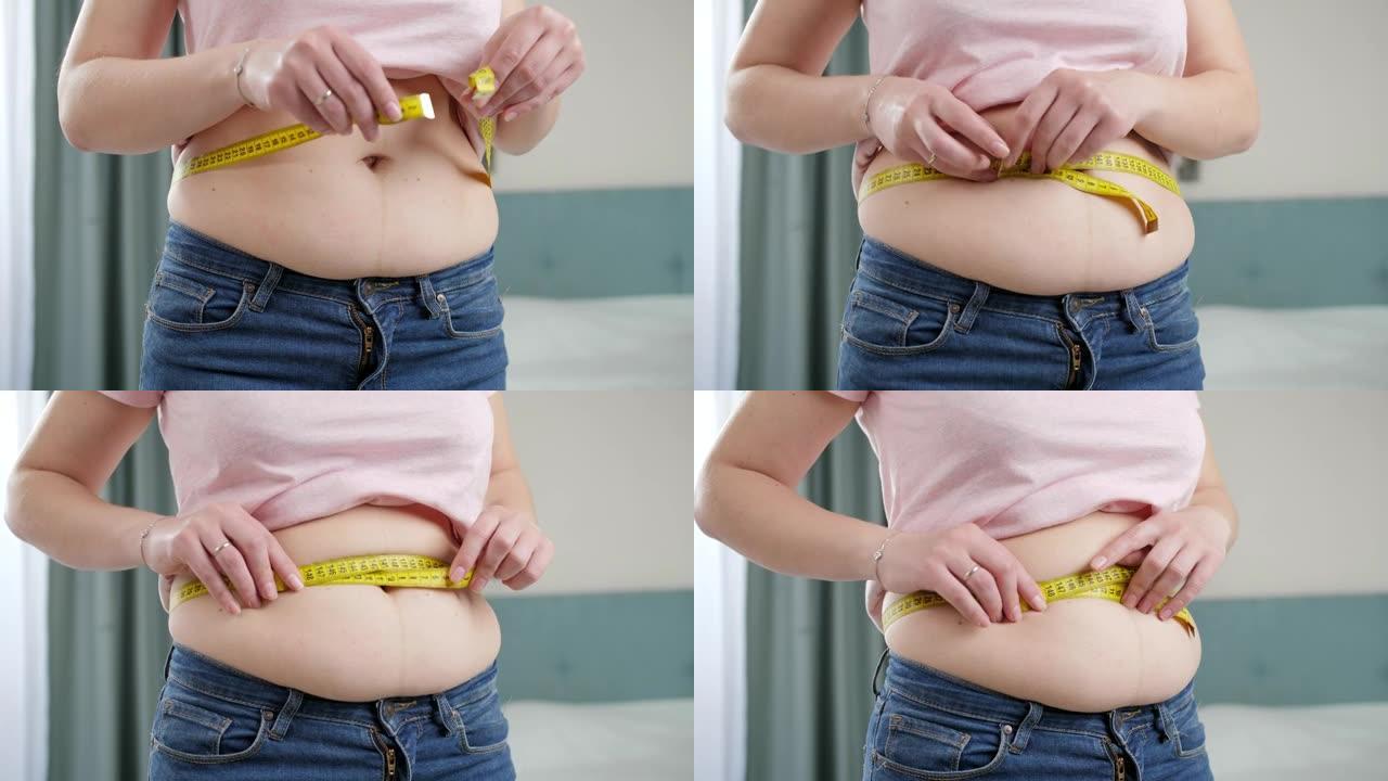 年轻女子用卷尺测量大胖的肚子。节食的概念，不健康的生活方式，超重和肥胖