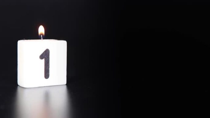 一根方形蜡烛，上面写着数字1被点燃并吹出，庆祝生日或周年纪念日。