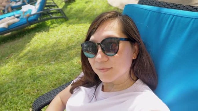 亚洲女性在酒店度假期间日光浴床上自拍，生活方式理念。