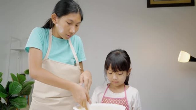 快乐的亚洲儿童在家学习制作饼干，女孩在搅拌碗中脱粒糕点面团。