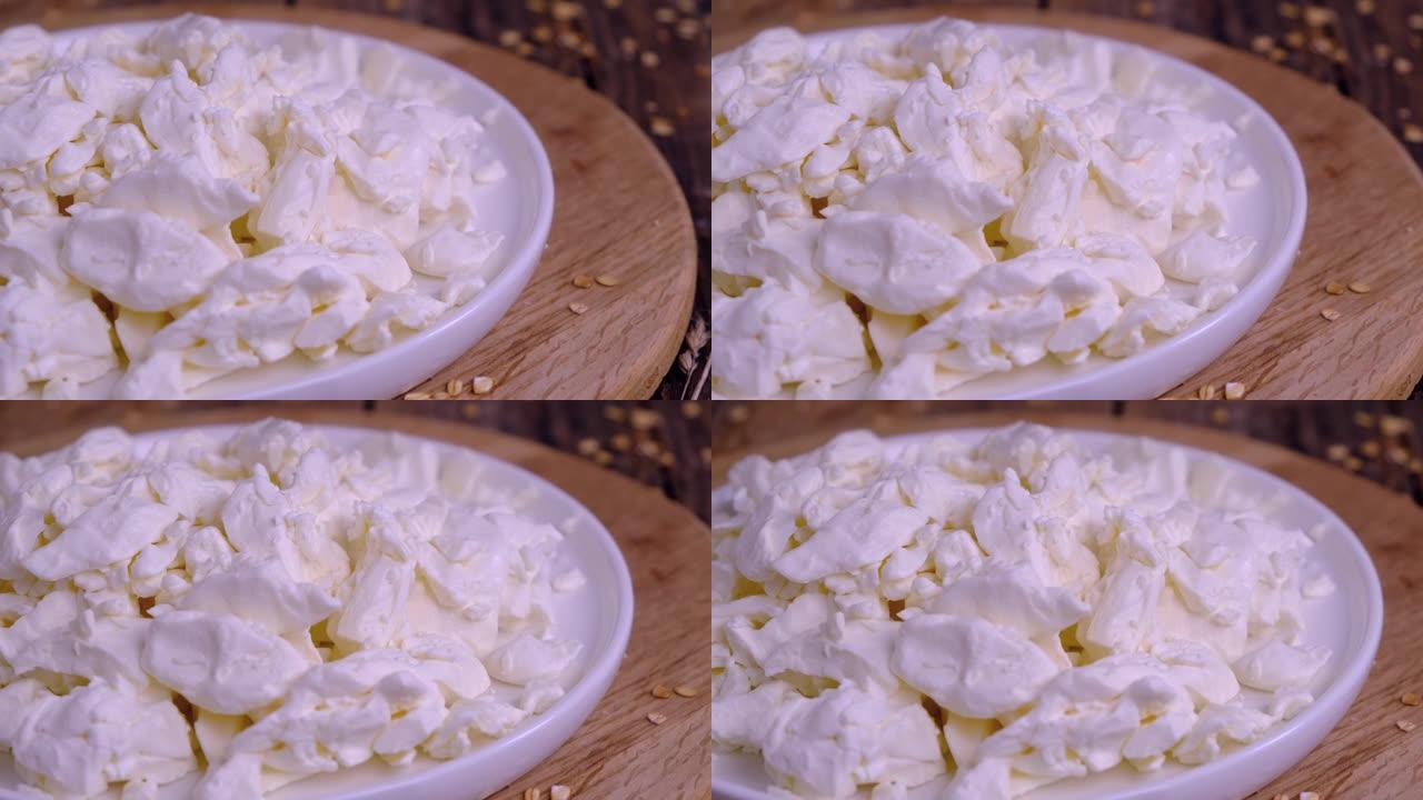 木制背景上的白色盘子上的奶酪特写