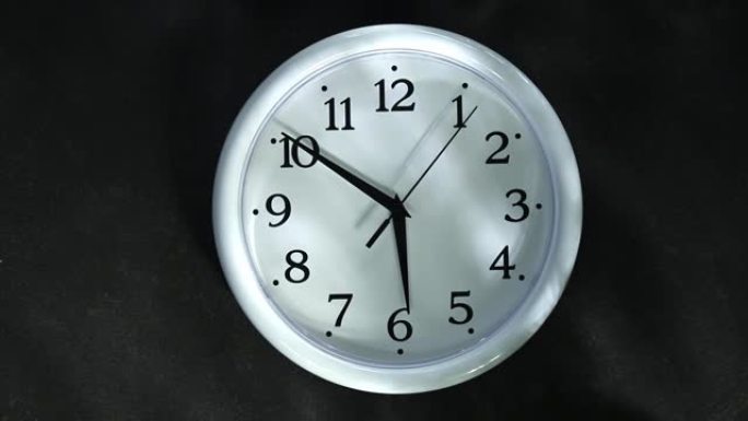黑色背景上的白色时钟。秒手去6点。晚上或早上。