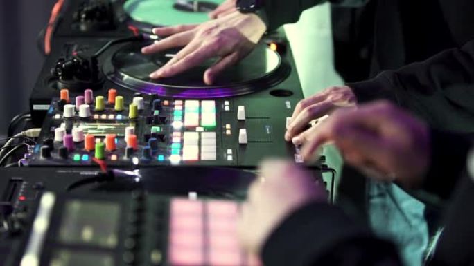 DJ集团使用控制台在迪斯科俱乐部混合舞蹈音乐。艺术。节目主持人乐队和混音甲板，特写侧视图。