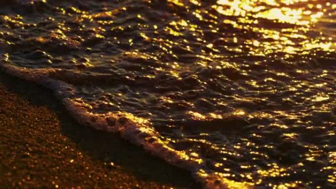 平静的海浪溅起金色沙滩。橙色日出反射海水