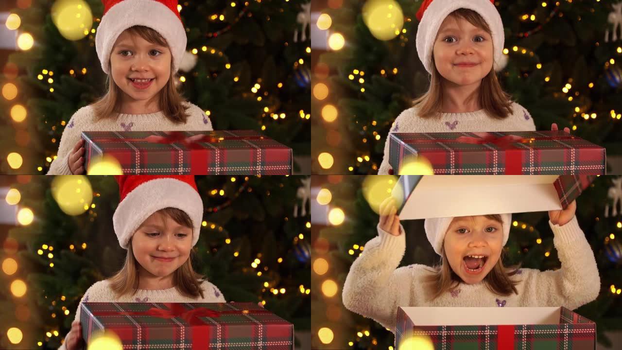 穿着红色圣诞老人帽子的快乐小女孩打开礼品盒，魔灯在圣诞树的背景上惊讶和大笑。新年