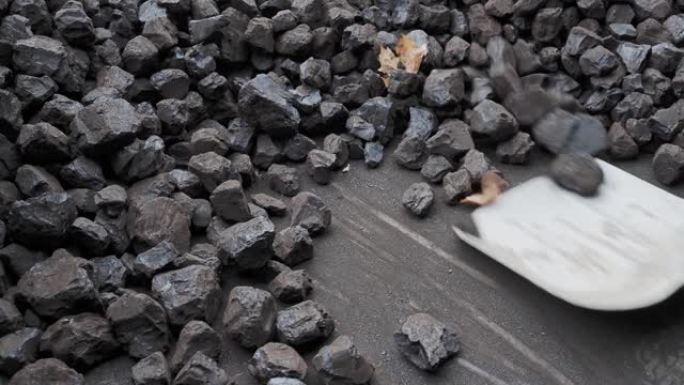 用铲子堆放一堆煤。供暖季的准备。