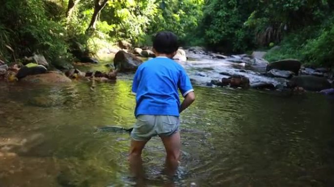 男孩在溪流中钓鱼男孩在溪流中钓鱼捞鱼
