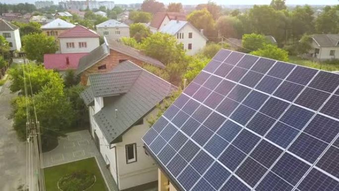 新的现代住宅小屋的空中俯视图，屋顶上有蓝色闪亮的太阳能光伏面板系统。可再生生态绿色能源生产理念。