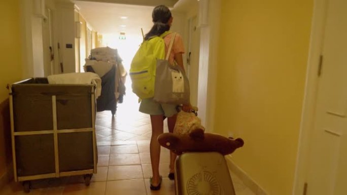 亚洲女孩从她的房间门口带着行李散步，在酒店或度假村度假期间退房，生活方式理念。